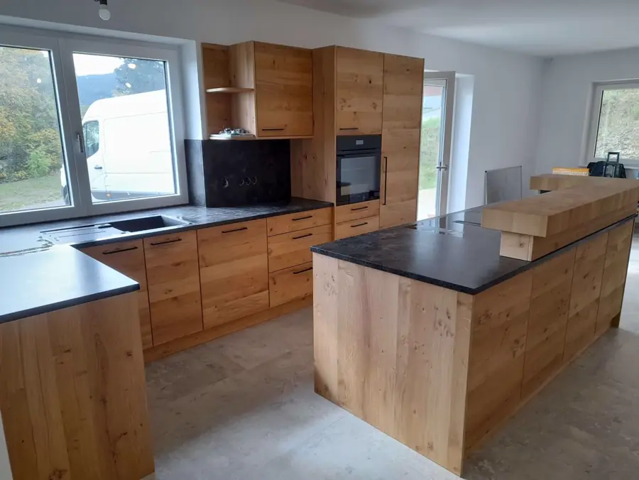 Maßküche aus Holz mit dunkler Arbeitsplatte und Kochinsel
